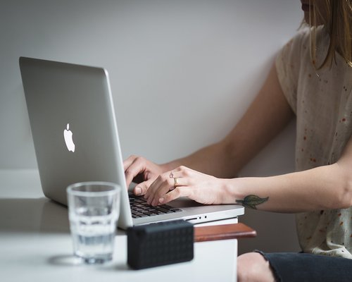 Glass of water on an office desk next to a laptop